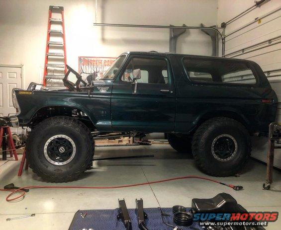 Dark green 1978 Ford Bronco, lifted, in garage with hood open and parts on floor