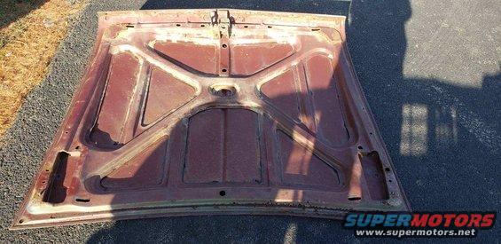 Underside of a rusty car hood, showing structural bracing