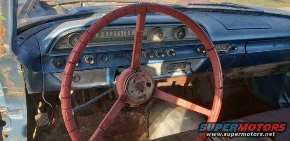 Interior of a blue 1961 Ford with a red steering wheel and dashboard gauges