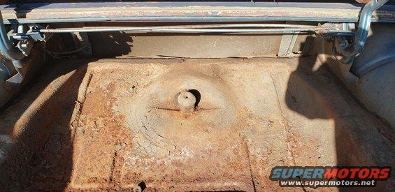 Rusty car trunk interior with visible spare tire well and latch mechanism