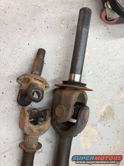 Two driveshaft assemblies with universal joints on a concrete floor
