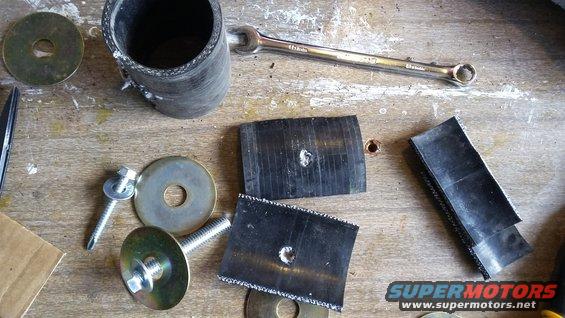 Rubber hose, bolts, washers, and a wrench laid out on a wooden workbench