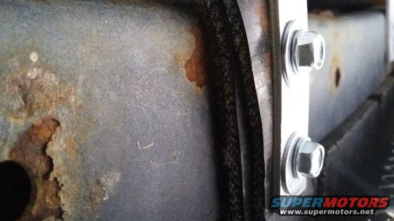 Rusted metal frame with two bolts securing a bracket