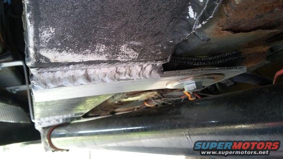 Welded metal bracket attached to vehicle frame with bolts and wiring visible