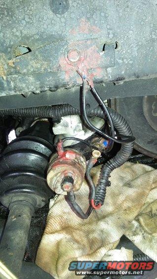 Close-up of starter motor wiring with red and black cables connected to terminals. A dirty rag is underneath