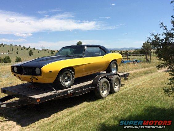 Yellow and black coupe on a trailer, looks like a 1969 Camaro but the grille is wrong