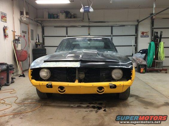 1969 Chevrolet Camaro front view, yellow bumper, black hood, in garage