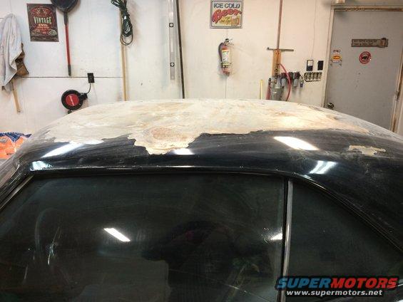 Car roof with body filler being applied. Garage interior visible