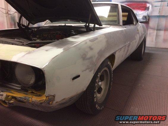 Front fender and hood of a 1969 Chevrolet Camaro being prepped for paint, showing primer and body filler