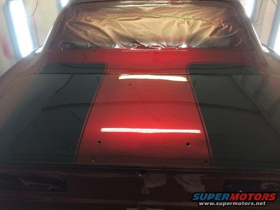Car trunk with red paint and black stripes, rear window covered with plastic