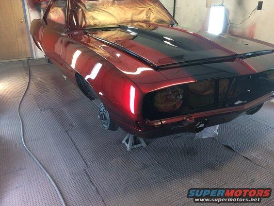 Red 1969 Chevrolet Camaro with black stripes, on jack stands in a garage