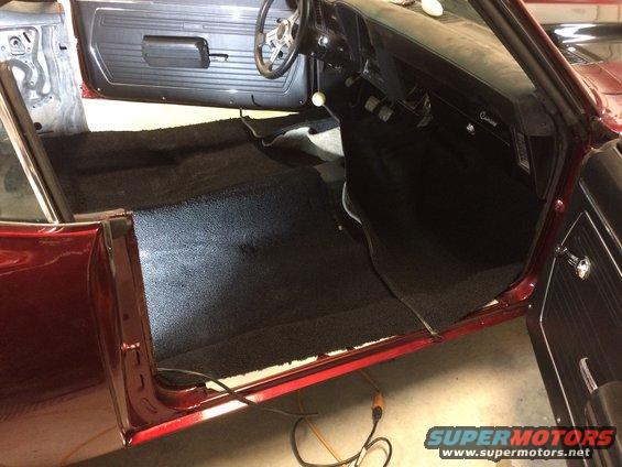 Interior of a 1969 Chevrolet Camaro with black carpet installed. Door panels and dashboard are visible