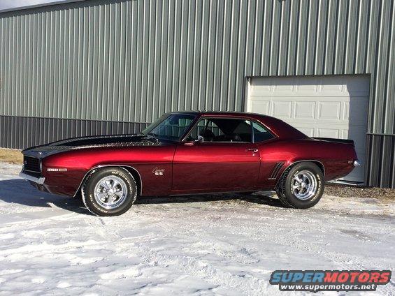 Red 1969 Chevrolet Camaro SS parked in front of a metal building with snow on the ground