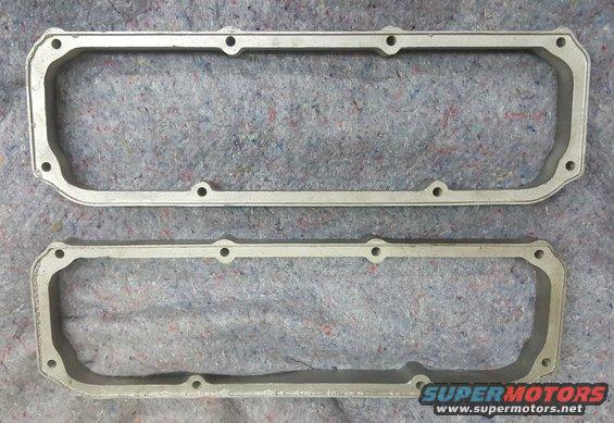 Two aluminum valve cover gaskets on a gray textured surface