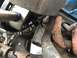 1989 Ford Bronco - Close-up view of engine components including hoses and a rusty exhaust manifold.