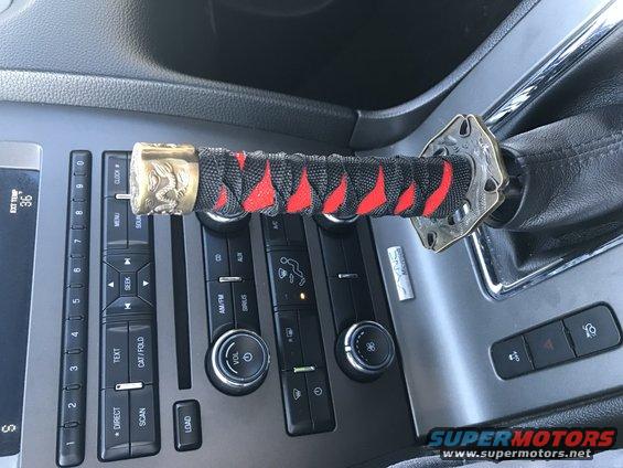 Car interior showing a custom gear shift knob resembling a katana handle, with visible climate controls and a 'SYNC' badge