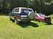 1993 Ford Bronco - A Ford Bronco with a spare tire on the back is parked next to a red Ford Mustang in a grassy field.