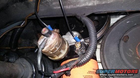 Engine oil filter with wiring connected to a component, and pulleys visible
