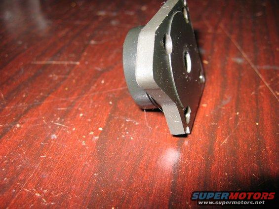 Metal part with four screw holes on a wooden surface