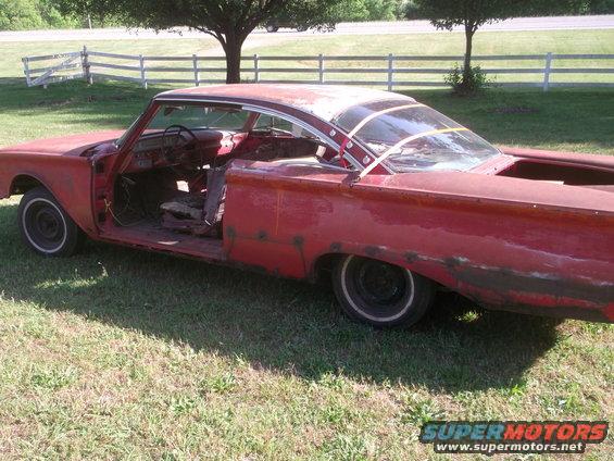 Red coupe project car, missing doors and interior parts, parked on grass