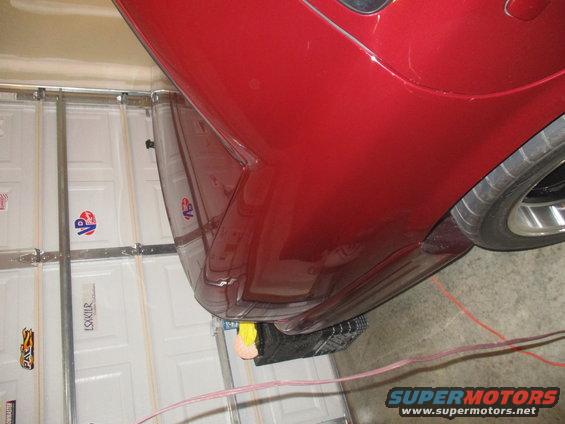 Red car rear quarter panel and tire, parked in a garage