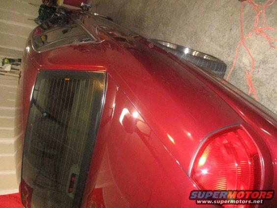 Red 2004 Ford Crown Victoria rear quarter panel with a taillight and tinted rear window with vertical blinds