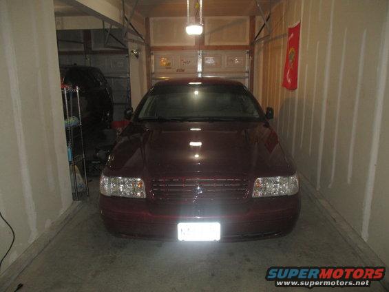 Maroon sedan parked in a garage. Headlights and grille are visible