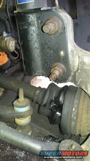 Close-up of a greasy CV joint boot, strut mount, and suspension linkage