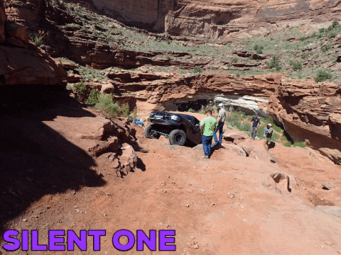 Off-road vehicle parked on dirt trail in a canyon. Text on ground says 'DIRT ONE'