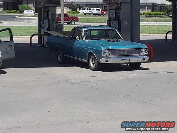 Blue pickup truck with a black tonneau cover at a gas station
