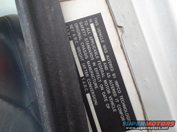 Compliance sticker on a vehicle door jamb, showing alteration details and weight