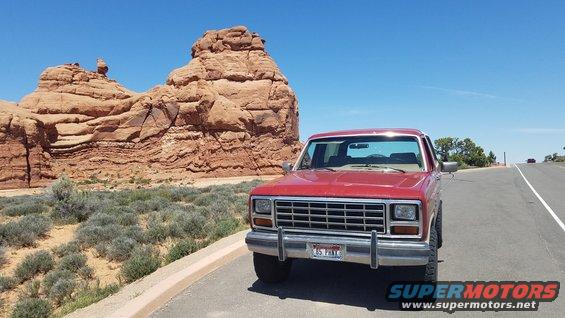 Red 1985 Ford Bronco front view parked on a road with desert landscape