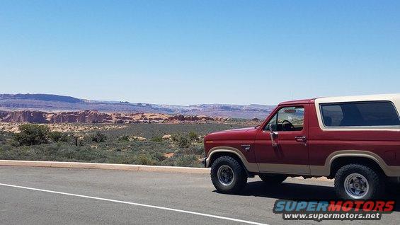 1985 Ford Bronco parked on the side of a road with a desert landscape in the background