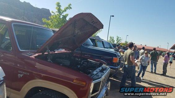 Maroon Ford Bronco with hood open, showing engine bay. Tan lower body trim visible