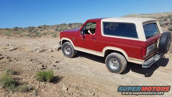 Red and tan 1985 Ford Bronco on a dirt road