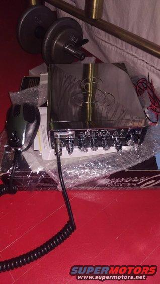 Chrome CB radio with black microphone and coiled cord on a red surface