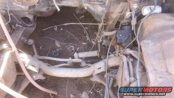 rusted car chassis with steering box and suspension parts visible
