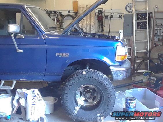 Blue 1996 Ford F-350 truck with hood open, lifted suspension, and large tires, parked in a garage