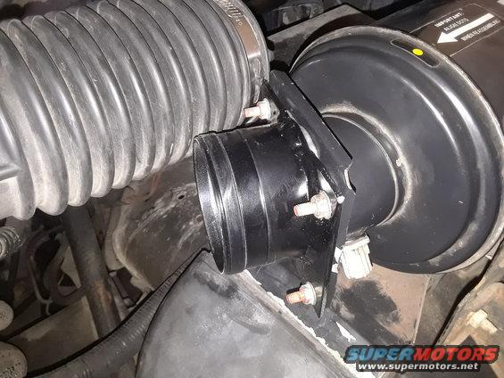 Close-up of engine air intake hose and housing. Some text is visible on the housing