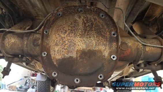 Underside view of a rusty rear differential cover with bolts