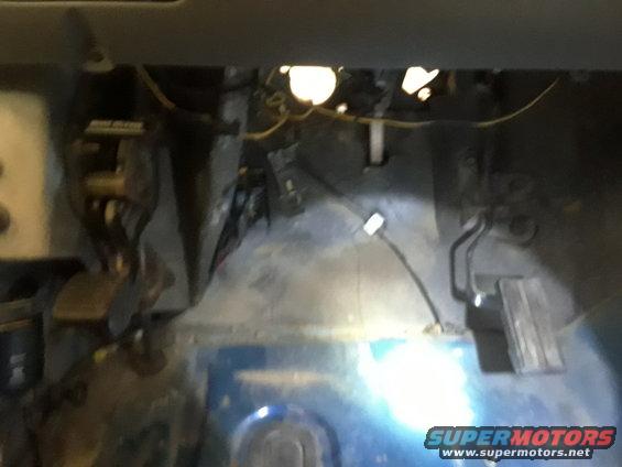 Blue vehicle interior floor with pedals and wiring visible. Supermotors.net logo in lower right