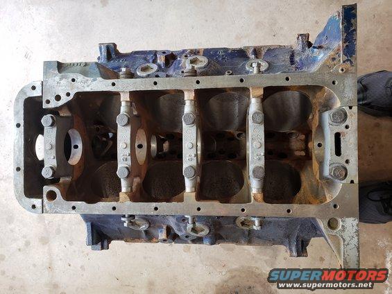 Engine block with main bearing caps installed. Some rust visible
