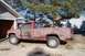 1988 Chevrolet Silverado 2500 - A muddy red 1988 Chevrolet Silverado 2500 pickup truck is parked outside a garage on a sunny day.