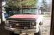 1988 Chevrolet Silverado 2500 - This red pickup truck is parked outside, with trees and a field visible in the background.