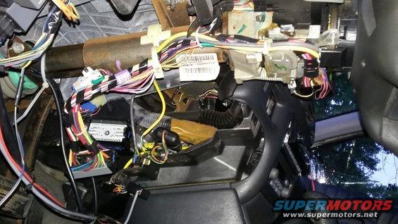 Close-up of a complex wiring harness and electrical components under a vehicle's dashboard