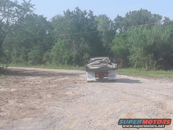 Flatbed truck with lumber, rear view, on a dirt road