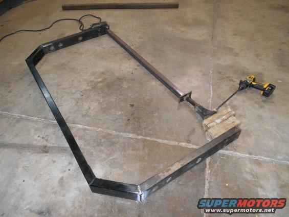 fabricated metal frame with a drill attached to a wooden block