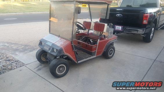 Red golf cart parked next to a black Ford pickup truck