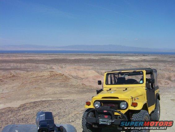 Yellow Toyota Land Cruiser FJ40 with soft top in desert landscape