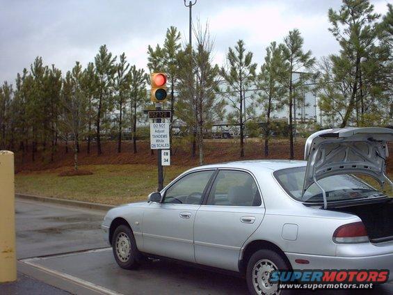 1995 Mazda 626 sedan, silver, with trunk open, parked near a traffic light and scales